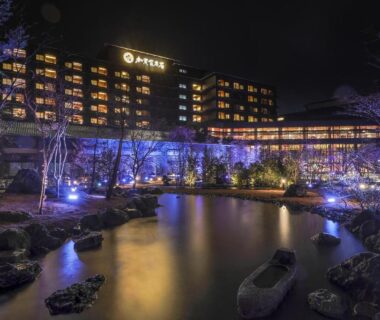 Night exterior with illuminated facade and pond reflections at Yamashiro Onsen Miyabi no Yado in Kaga, Ishikawa