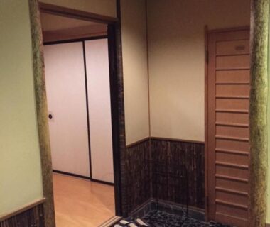 Stone genkan with pebble floor, wooden lattice door and tatami room visible at Yamashiro Onsen Yuzankaku in Ishikawa