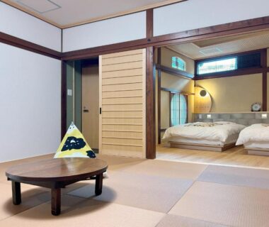 Spacious tatami room with low round table, sliding wooden doors and two beds at Yamatoya in Hyōgo