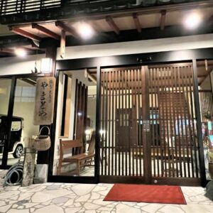 Nighttime entrance with wooden lattice doors, stone paving and warm lantern lighting at Yamatoya in Hyōgo, Kansai