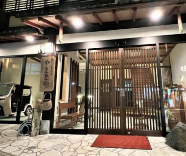 Nighttime entrance with wooden lattice doors, stone paving and warm lantern lighting at Yamatoya in Hyōgo, Kansai