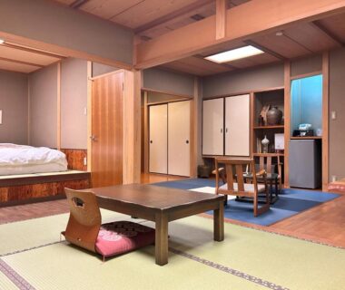 Tatami room with low table, cushion, sliding doors and raised bed at Yamatoya, Hyōgo