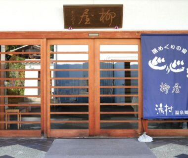 Wooden sliding doors with blue noren and signboard at Yanagiya entrance in Yamanashi