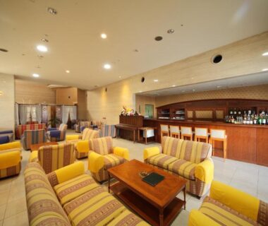 Comfortable striped sofas and wooden tables in Yanagiya lounge with a bar counter, bright tiled floor and warm lighting, Wakayama