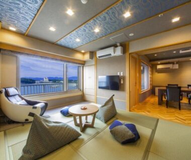 Tatami room with low table, floor cushions and sea view from large window at Yanagiya Wakayama
