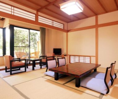 Spacious tatami room with low table, floor chairs, shoji screens and garden view at Yanagiya in Yamanashi
