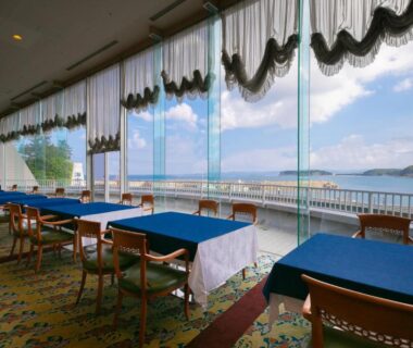 Dining area with tables and large windows overlooking a bay and islands at Yanagiya, Wakayama, Japan