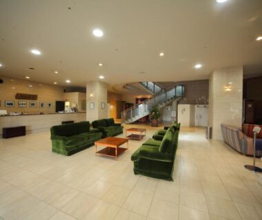 Green velvet sofas, wooden tables and central staircase in Yanagiya lobby, Wakayama, Kansai, Japan