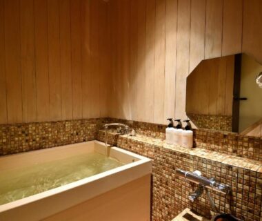 Indoor wooden bathtub with mosaic tile surround and wall-mounted shower at Yasaka Yutone Kyokoyado Kyoto
