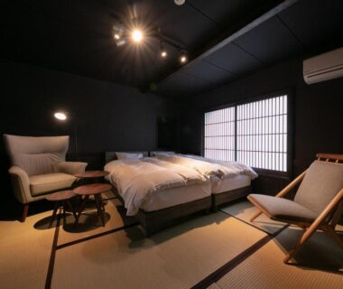 Twin beds on tatami floor with shoji screen and lounge chairs in Yasuraginoyado Yufu room, Ōita