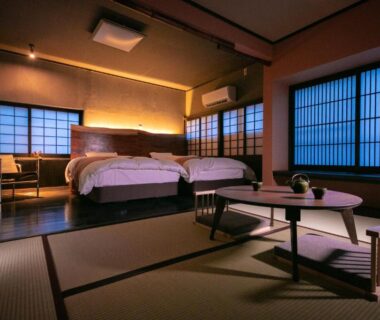 Tatami-floored room with twin beds, shoji screens, low table and warm lighting at Yasuraginoyado Yufu, Ōita