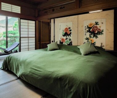 Tatami room with twin green-covered beds, shoji screens and painted fusuma overlooking garden at Yatsusankan Gifu