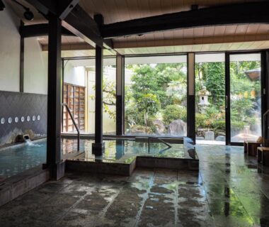 Indoor onsen bath with stone floor and garden view at Yatsusankan in Gifu Prefecture