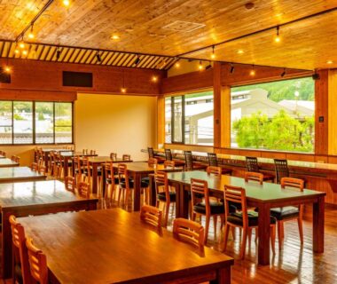 Warm wooden dining room at Yawaragi-no-Sato Yadoya with large windows overlooking Ōita hillside