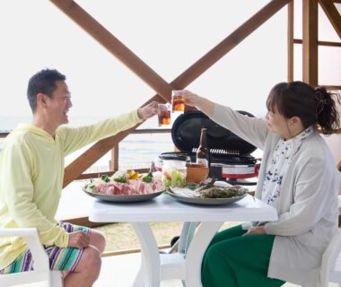 Couple clinking glasses over assorted dishes on a covered terrace at Yodoya in Hyōgo, Kansai.
