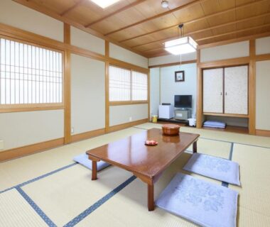 Traditional tatami room with low table, zabuton cushions, shoji screens and television at Yodoya, Hyōgo