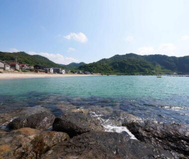 Rocky shore and turquoise bay with small beachfront houses near Yodoya in Hyōgo, Japan