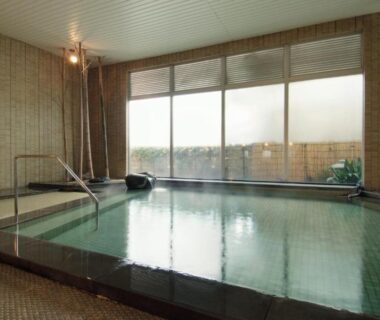 Tiled indoor onsen pool with handrail and floor-to-ceiling windows at Yokikan in Shizuoka, Chūbu