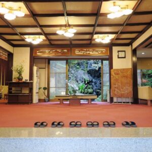 Traditional ryokan entrance with lined slippers, reception desk and inner garden at Yokikan in Shizuoka