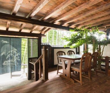 Covered wooden terrace dining area with table and chairs, noren and garden view at Yokohama Fujiyoshi Izuten Shizuoka