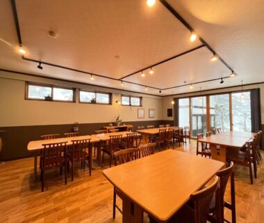 Wooden dining tables and chairs in a bright hall at Yokokura Ryokan, Nagano