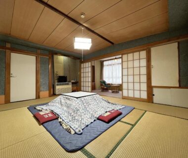 Traditional tatami room with futon and low table with blanket, shoji screens and wooden ceiling at Yokokura Ryokan in Nagano