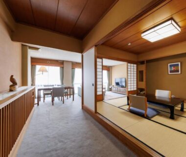 Tatami room with low table, floor cushions, shoji screens and seating area at Yorozuya Nagano