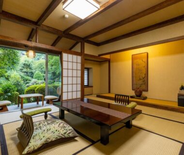 Traditional tatami room with low table and shoji doors opening to garden at Yoshiike Ryokan, Kanagawa, Japan