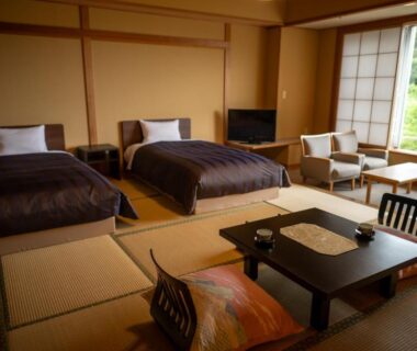 Tatami room with twin beds, low table, shoji screens and window overlooking green landscape