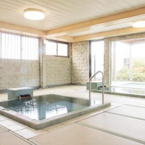 Indoor stone onsen bath on tatami flooring with large windows overlooking garden at Yoshino, Shizuoka