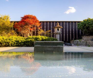 Reflective outdoor pool with stone lantern and red maple in Yoshino ryokan garden, Shizuoka