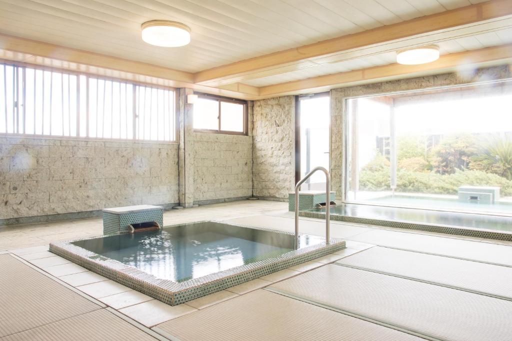 Indoor Onsen Bath at Yoshino Shizuoka Indoor stone onsen bath on tatami flooring with large windows overlooking garden at Yoshino, Shizuoka