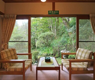 Relaxing sitting area with wooden chairs and low table facing lush garden at Yoshinoonsen Motoyu in Nara