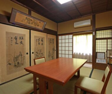 Tatami room with low wooden table, chairs and painted fusuma panels at Yoshinoonsen Motoyu in Nara