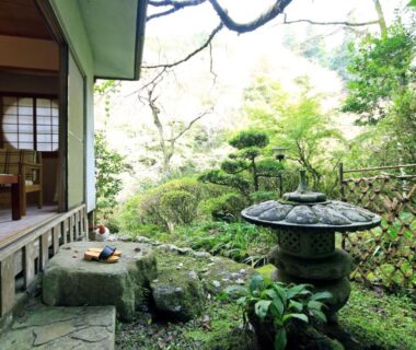 Engawa veranda opening onto moss garden with stone lantern, tatami room and low wooden table visible