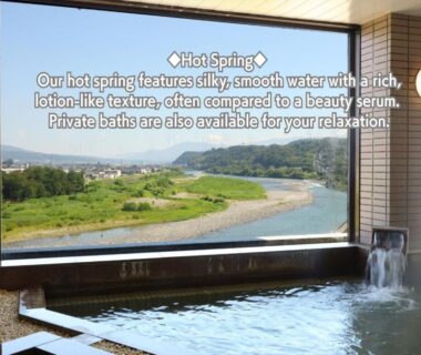 Indoor hot spring bath with large window overlooking river and mountains at Yoshinotei in Nagano