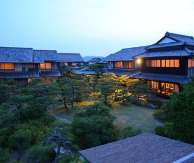 Traditional wooden ryokan buildings around a lit garden courtyard at Yoyokaku in Saga, Kyūshū