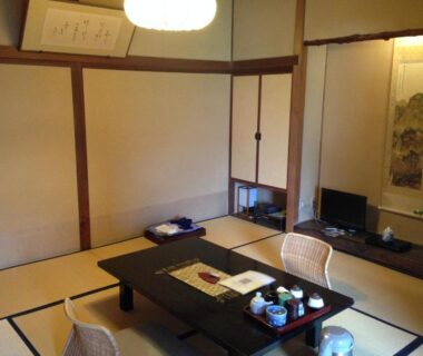 Traditional tatami room with low table, woven chairs, tokonoma scroll and tea set at Yoyokaku in Saga