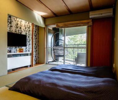 Traditional tatami room with futon bedding, shoji screens, balcony and hanging chair overlooking lush greenery