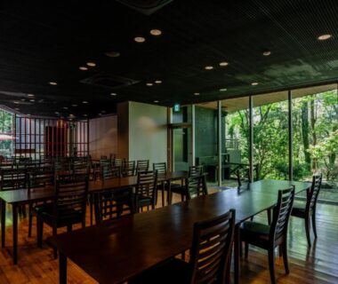 Wooden dining tables and chairs with floor-to-ceiling windows overlooking a serene garden at YuYu Hakone in Kanagawa