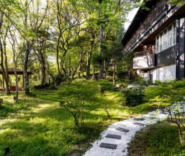 Stone path through moss garden beside traditional wooden ryokan building at YuYu Hakone, Kanagawa