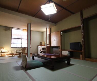 Traditional tatami room with low table, zabuton cushions, tokonoma alcove and seating area at Yuasobiyado Akebono in Niigata
