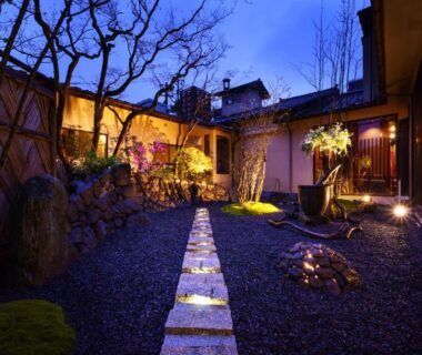 Evening illuminated stone path through a gravel courtyard with lanterns and wooden ryokan facades at Yuasobiyado Akebono, Niigata