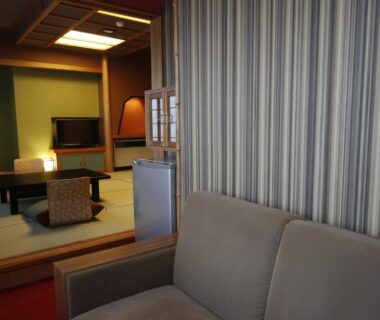 Tatami seating area with low table, zabuton cushions, tokonoma and sofa at Yuasobiyado Akebono in Niigata