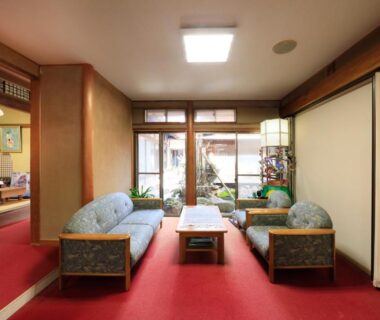 Seating area with sofas, low table, shoji screens and tatami room visible at Yudanaka Seifuso, Nagano