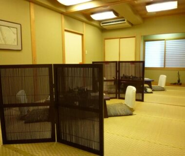 Tatami-floored communal lounge with bamboo screens, floor chairs and shoji windows at Yudanaka Tawaraya Ryokan Nagano