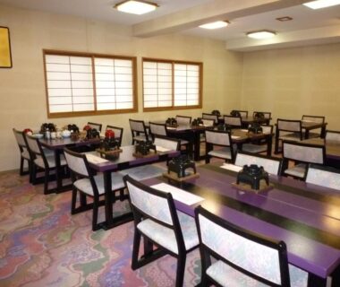 Communal dining room with wooden tables and upholstered chairs at Yudanaka Tawaraya Ryokan in Nagano