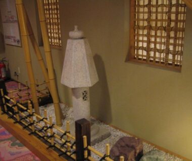 Stone lantern beside small indoor rock garden with bamboo lattice at Yudanaka Tawaraya Ryokan, Nagano
