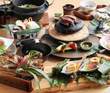 Assorted small dishes and bowls on wooden trays for traditional ryokan multi-course dining in Ōita