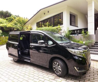 Black passenger van with open sliding door at Yufudake Ichibo no Yado Kirara entrance, Ōita